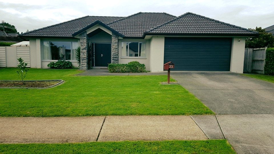 A freshly mown front lawn with mower stripes in front of a single-storey home with a grey tiled roof
